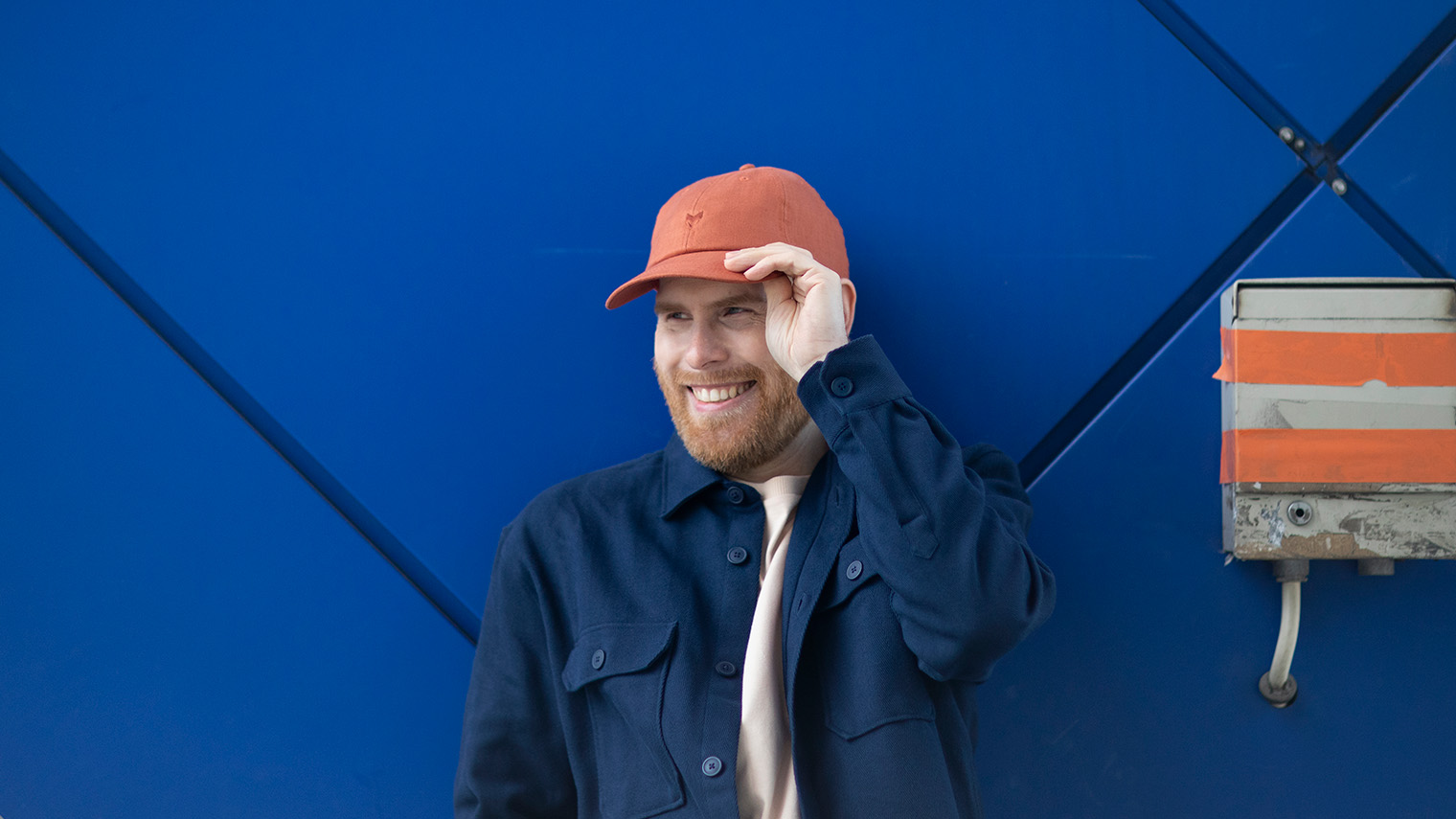 Mies pitää kättä lippalakin lipalla.