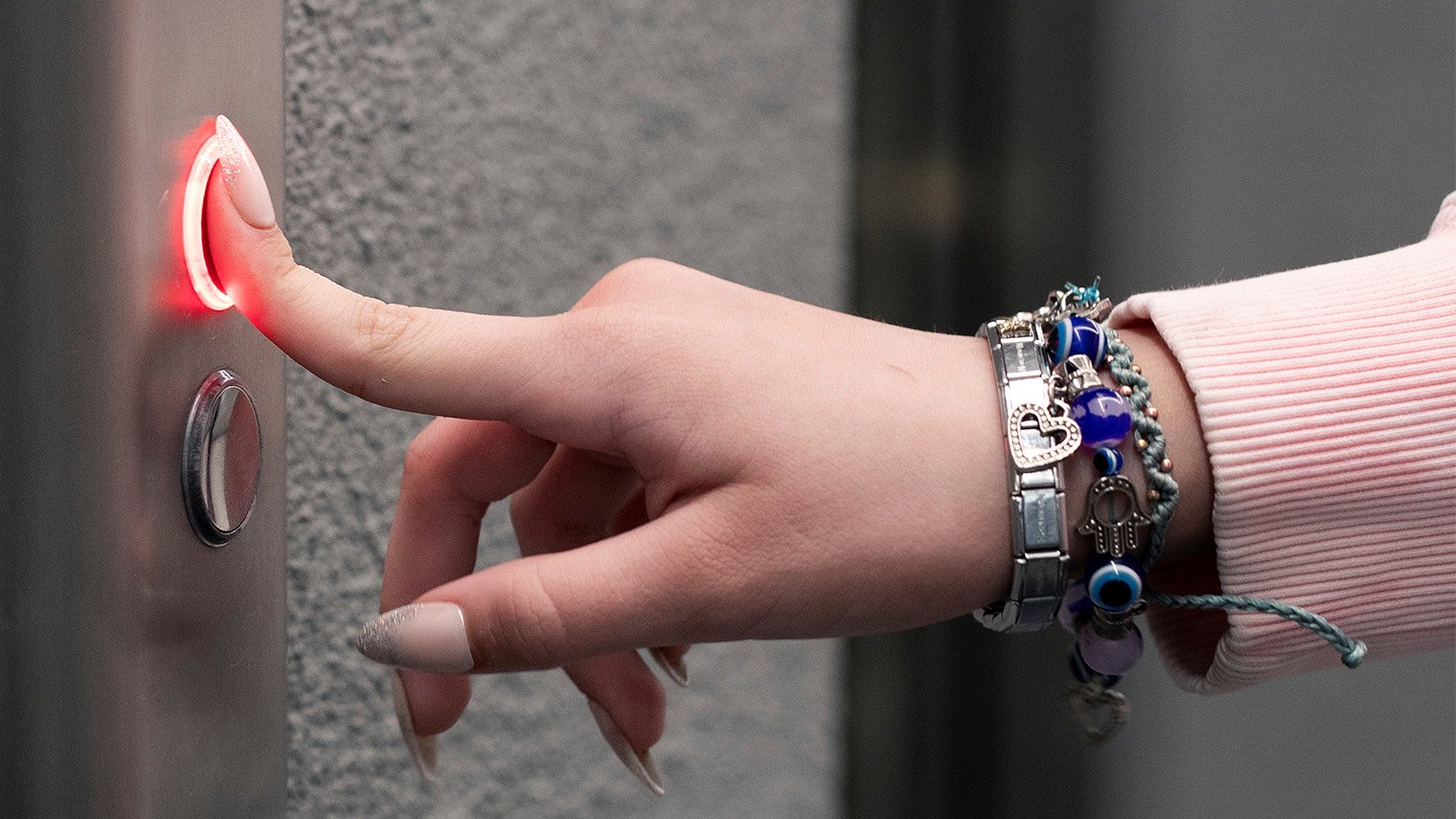 Sormi painaa hissin nappia.