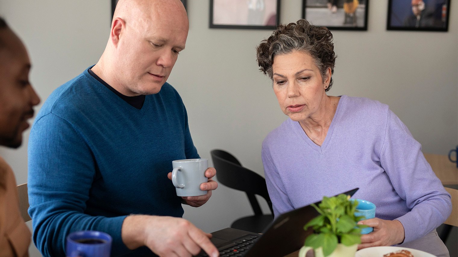 Työporukka kahviossa läppärin äärellä.